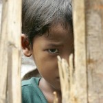 A karen boy looks through bamboo at Tham